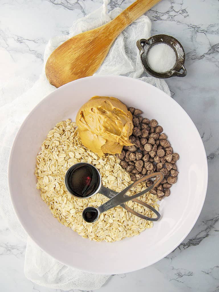 ingredients oats, maple syrup, peanut butter, chocolate chips, vanilla in a white bowl