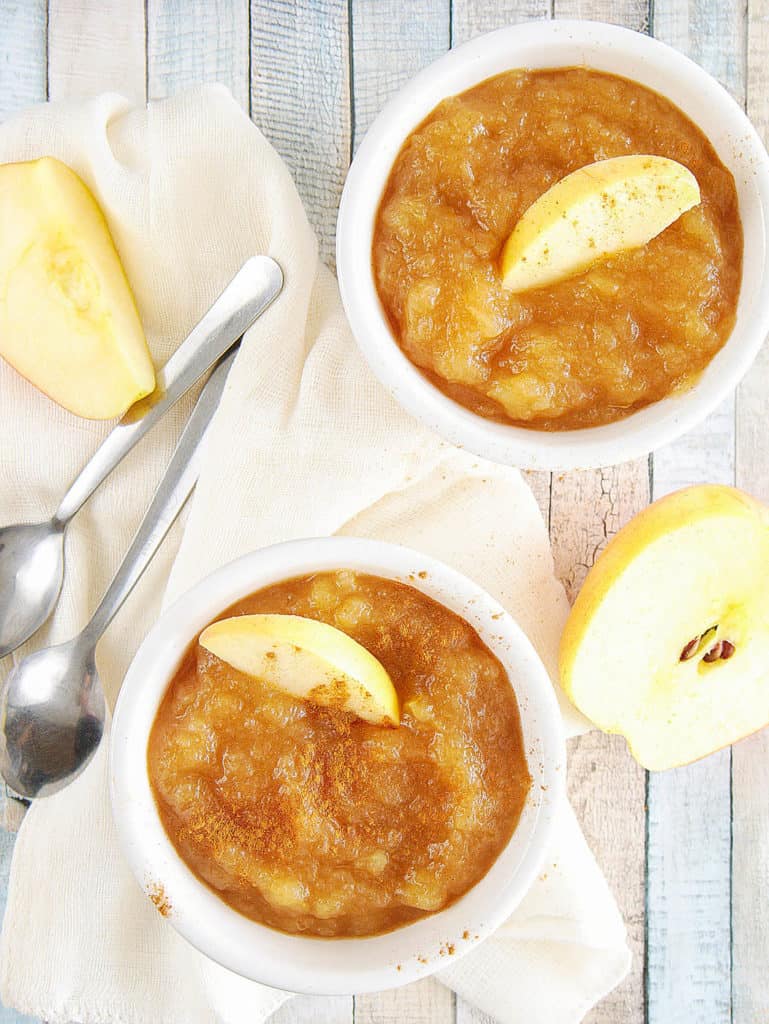instant pot applesauce with cinnamon and honey, in a white ramekin with a sliced apple on top, top view