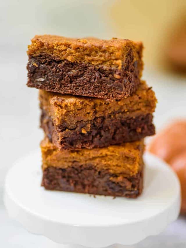 Pumpkin brownies stacked on a little cake stand.