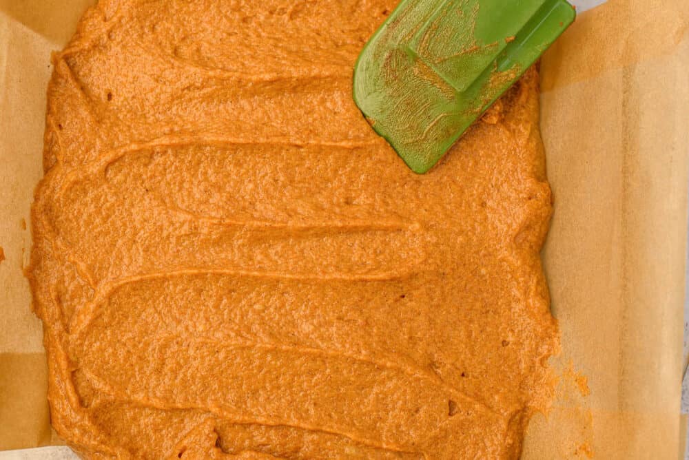 pumpkin batter spread on top of chocolate layer in baking pan