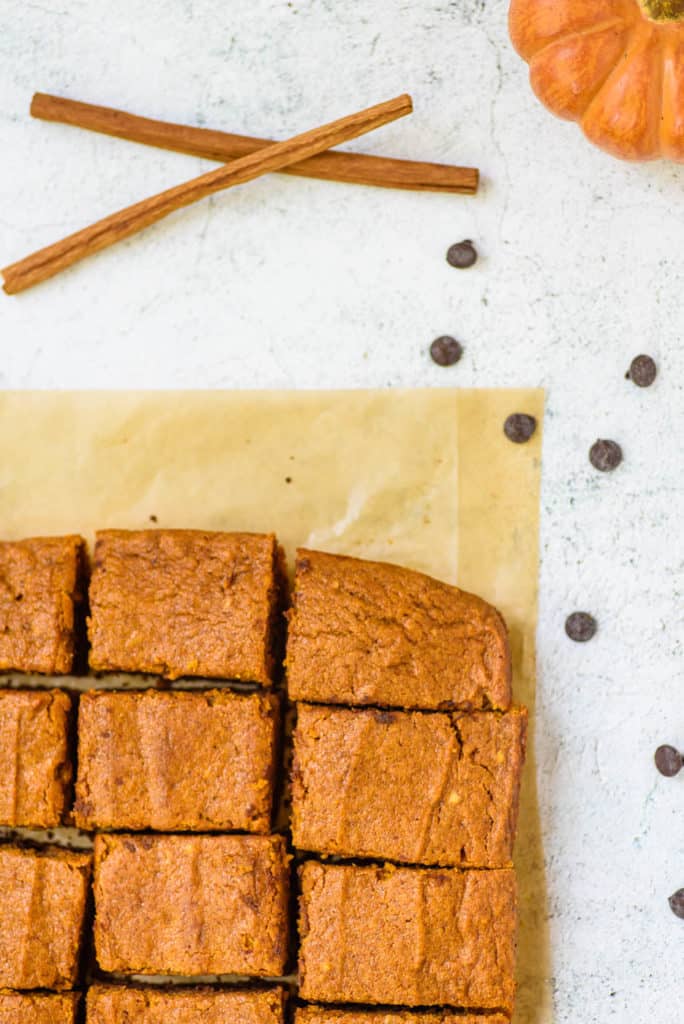 layered pumpkin brownies fresh out of the oven, cut into squares on parchment paper, top view