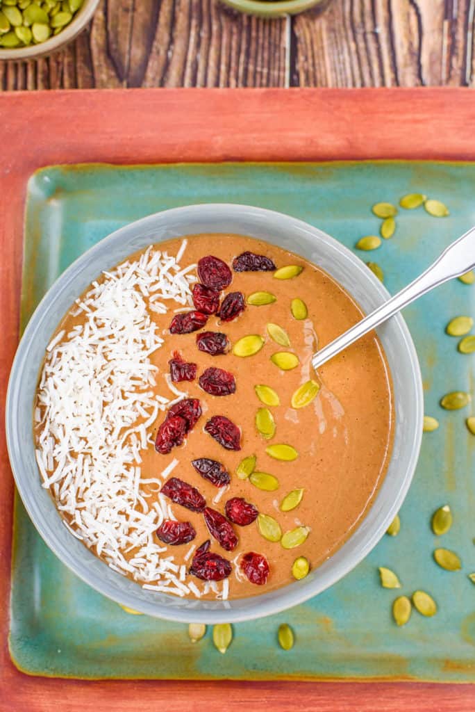 pumpkin smoothie bowl topped with coconut, cranberries, and pumpkin seeds