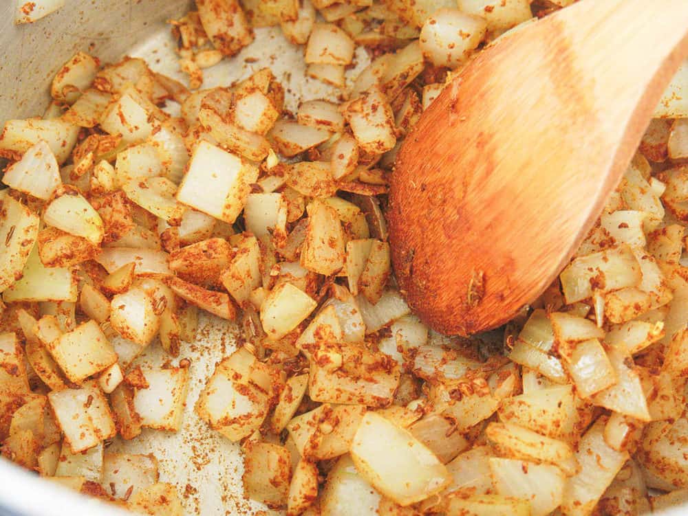 spices added to onion and garlic mixture in a pot