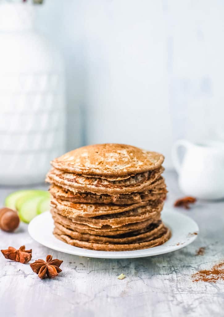 stacked apple cinnamon pancakes on white plate