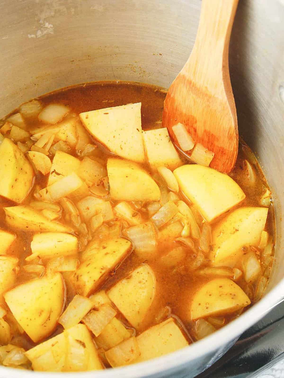 Potatoes and onions cooking in a pot on the stove.