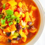 butternut squash chili served in a white bowl topped with green onions