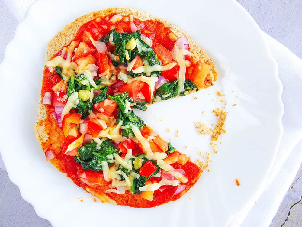 healthy vegetarian flatbread pizza recipe - topped with fresh veggies, served on a white plate