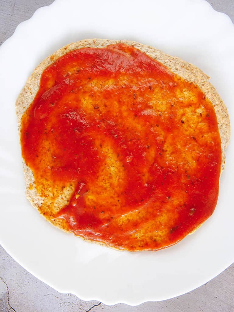 tortilla with pizza sauce spread on it