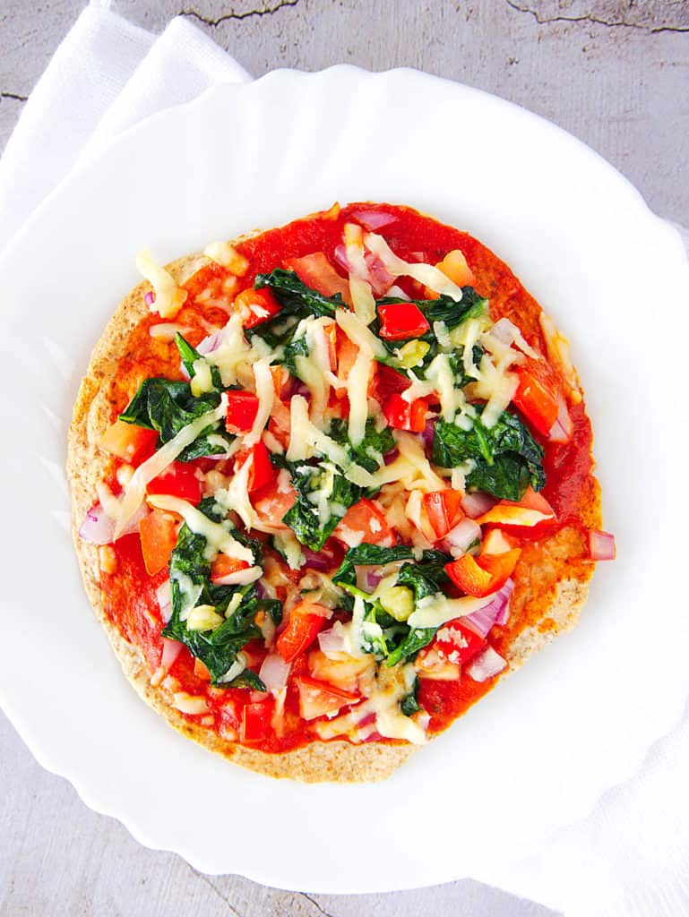 healthy vegetarian flatbread pizza recipe - topped with fresh veggies, served on a white plate