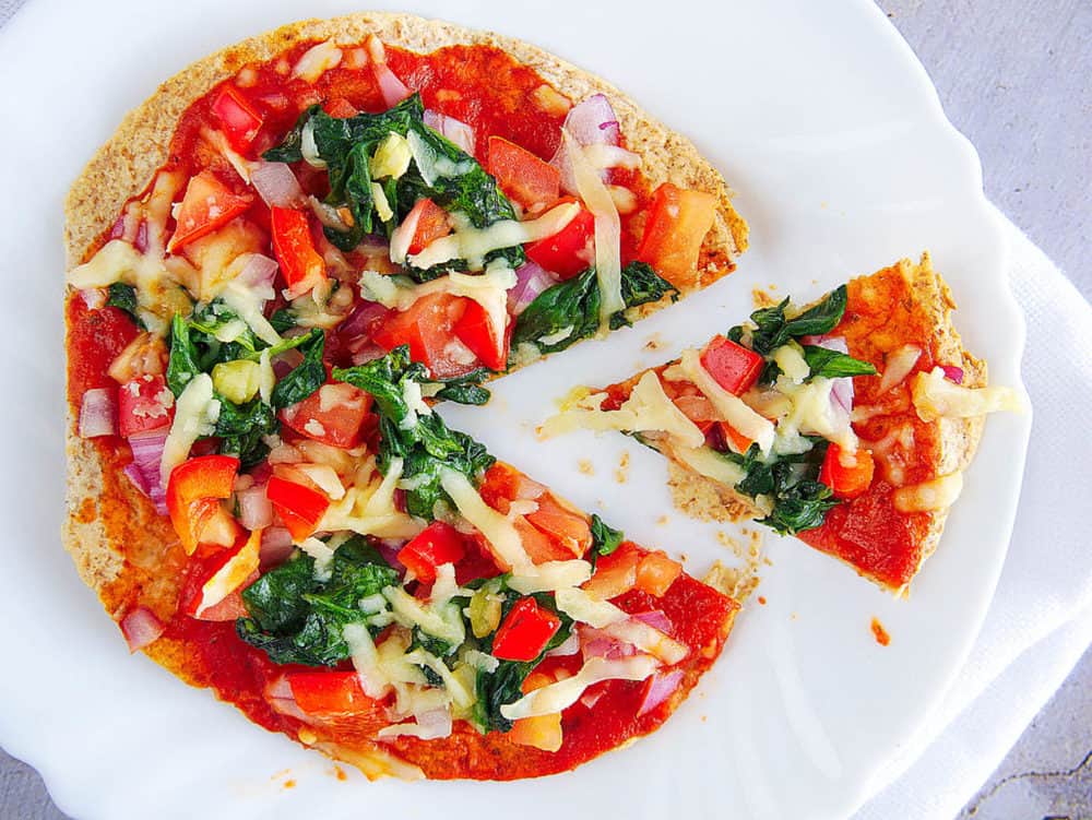 healthy vegetarian flatbread pizza recipe topped with fresh veggies, served on a white plate 