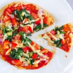 healthy vegetarian flatbread topped with fresh veggies, served on a white plate