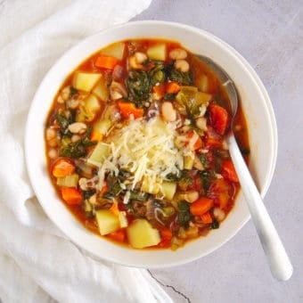 healthy minestrone soup, served in a white bowl, top view