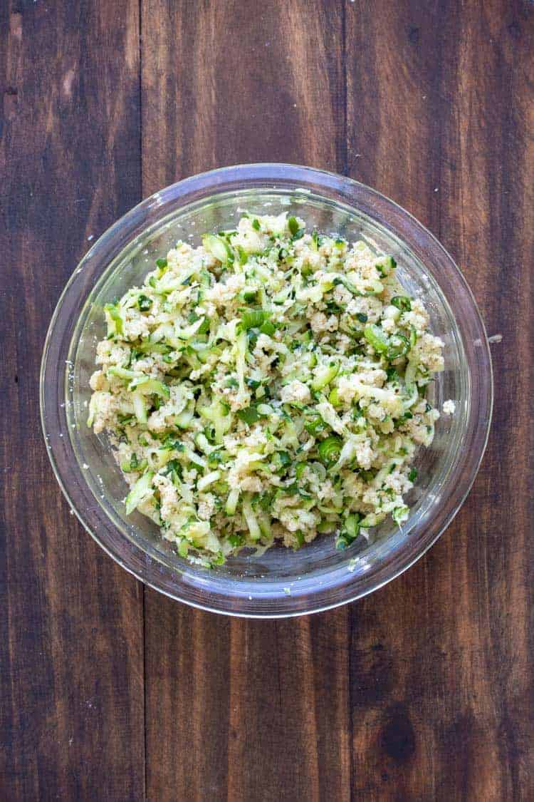 Glass bowl filled with raw zucchini fritter mixture