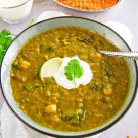 Lentil and swiss chard soup in a grey bowl with a dollop of yogurt on top.