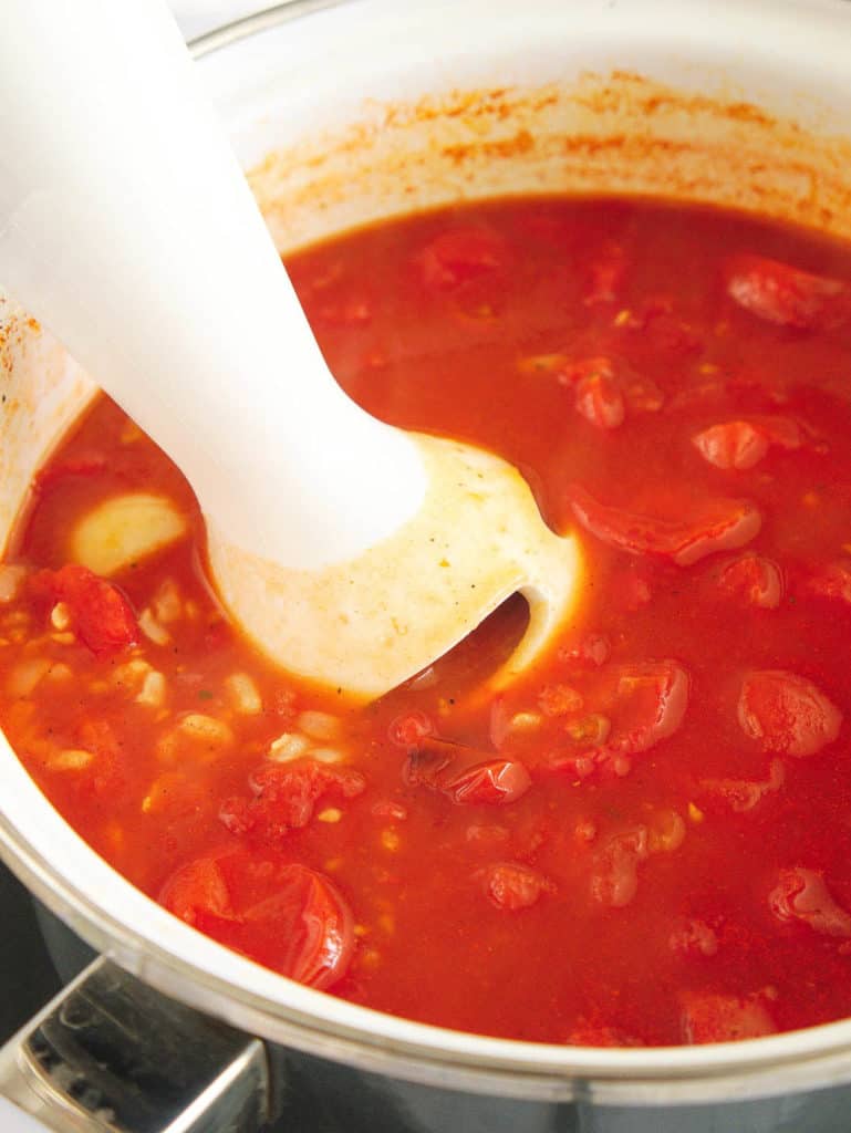 tomato soup simmering in a pot, blended with an immersion blender