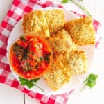 crispy air fryer ravioli with marinara sauce, served on a white plate with sauce on the side, top view