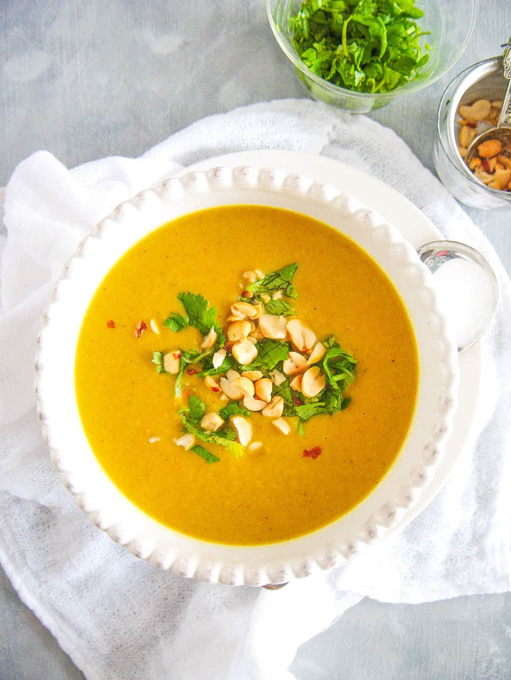 spicy cauliflower soup, topped with crushed cashews and cilantro, served in a white bowl