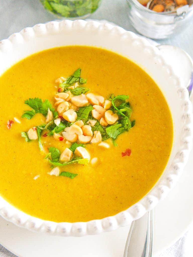 spicy cauliflower soup, topped with crushed cashews and cilantro, served in a white bowl - 30 minute vegetarian meals