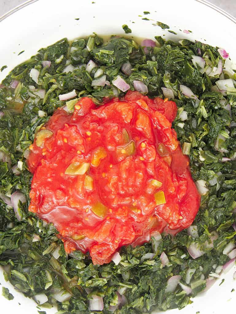 tomatoes added to spinach mixture in pan