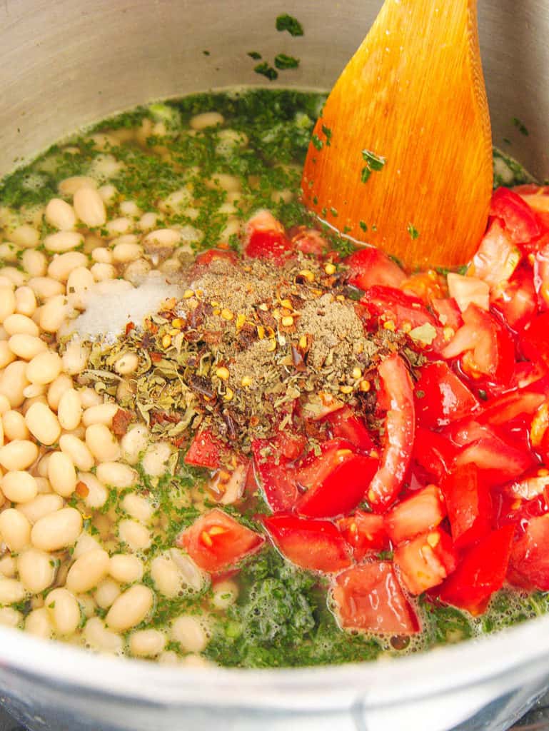 tomatoes beans broth spices added to pot with kale