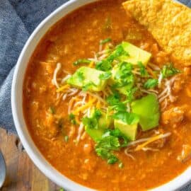 Mexican bean soup served in a bowl topped with avocado and tortilla chips.