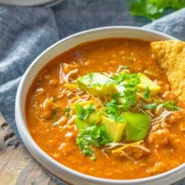 Mexican bean soup served in a bowl topped with avocado and tortilla chips.