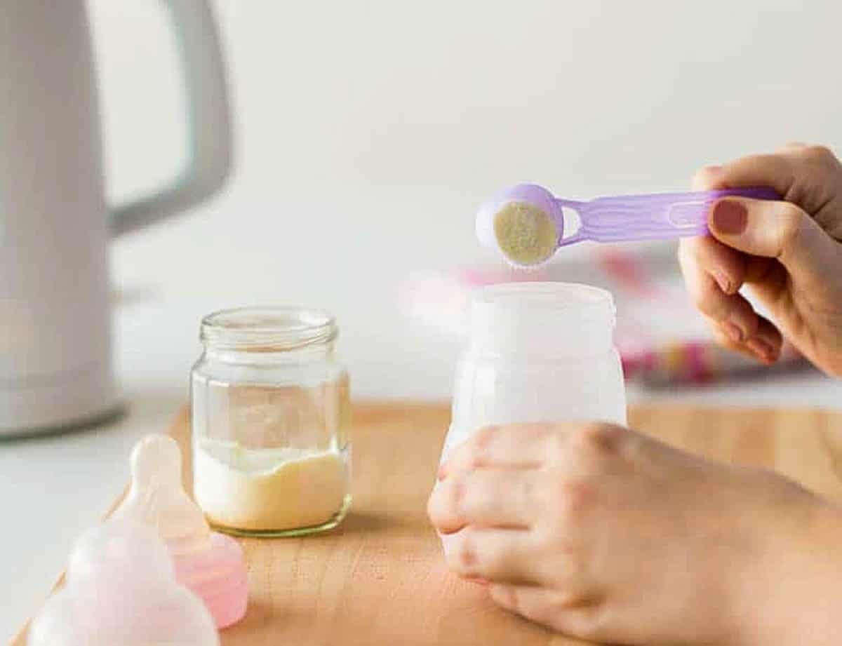 Adult hand mixing hypoallergenic formula in a baby bottle.