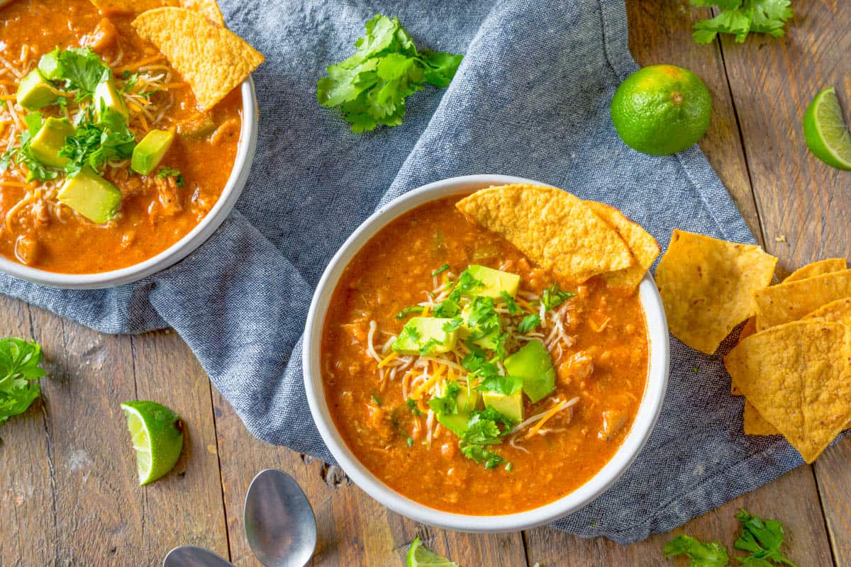 Mexican bean soup served in a bowl topped with avocado and tortilla chips.