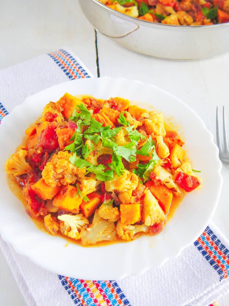 roasted cauliflower curry with sweet potatoes topped with cilantro, served on a white plate - baby dinner recipes