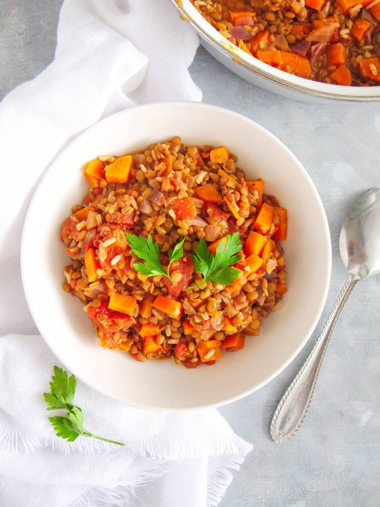 indian stew with rice and lentils, served in a white bowl with cilantro on top