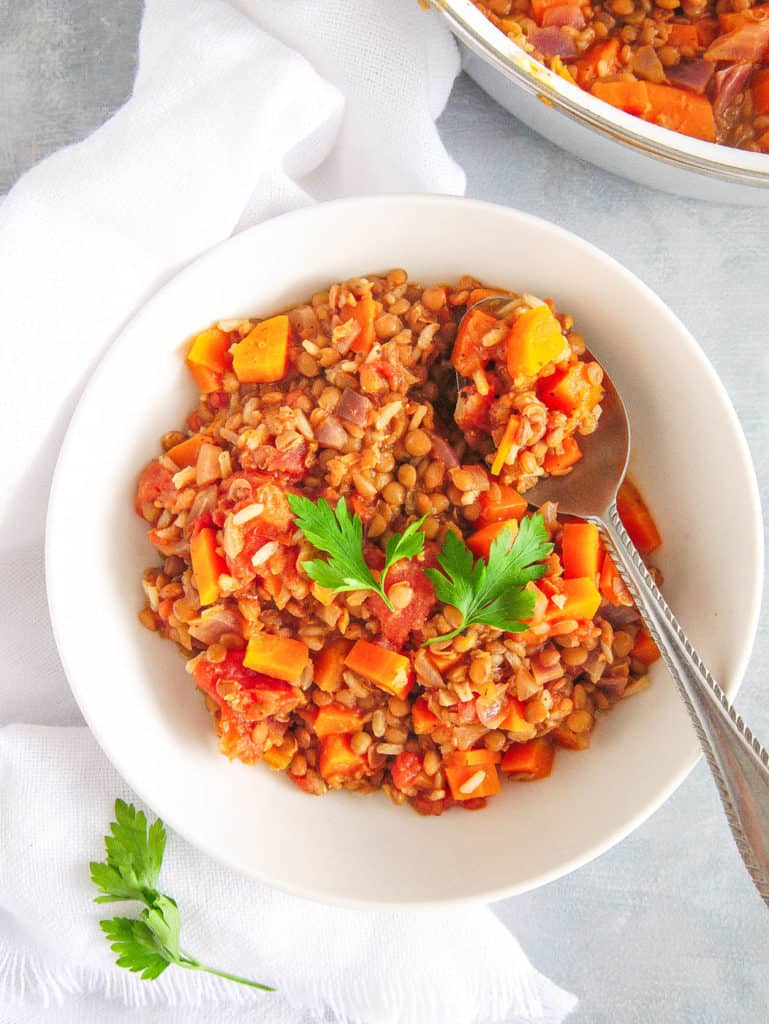 indian stew with rice and lentils, served in a white bowl with cilantro on top