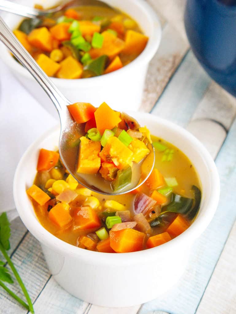 spoonful of thai sweet potato soup with poblano peppers served in a white bowl