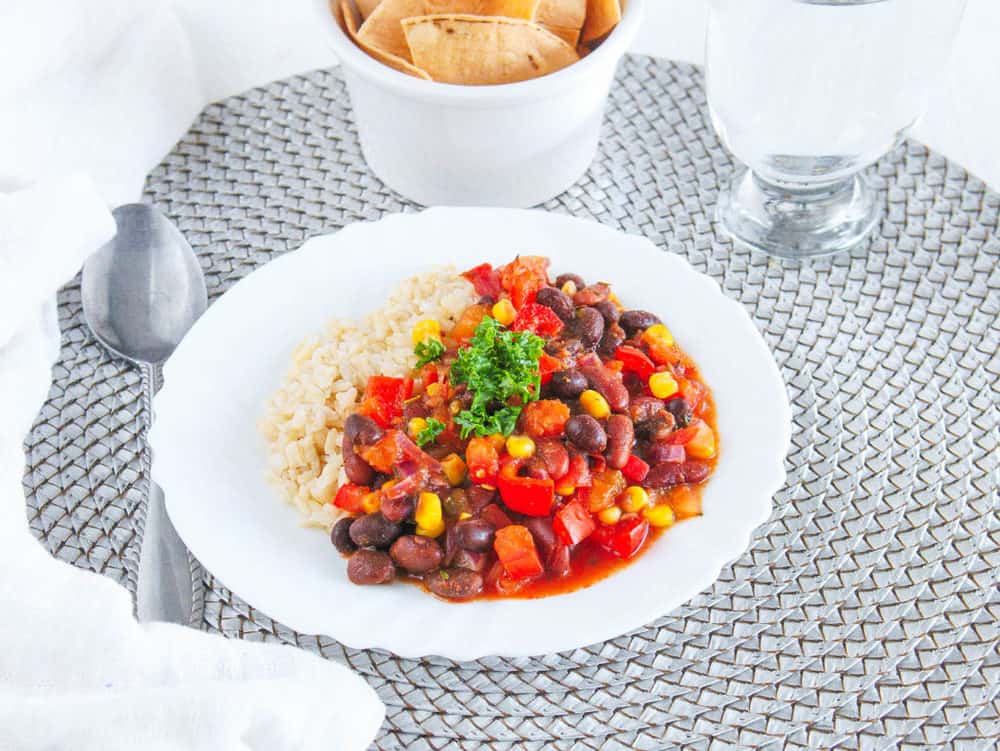 vegetarian stew recipe with beans and rice, served on a white plate with a spoon