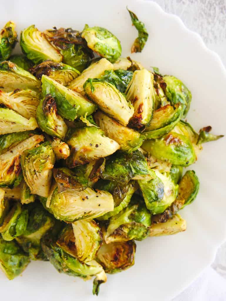 closeup of air fryer brussel sprouts served on a white plate, top view