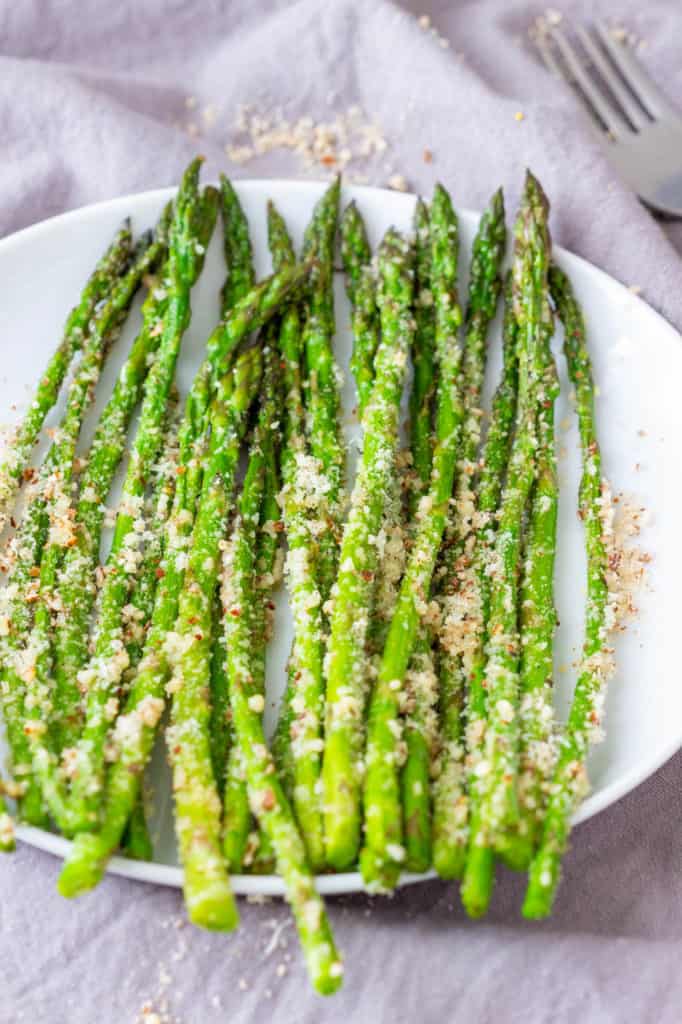 steamed asparagus with pecorino, served on a white plate