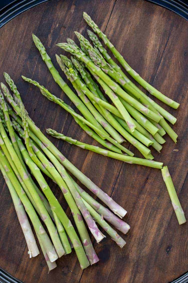 Crispy, crunchy, loved by the entire family and easy to throw together. This asparagus fries recipe makes the perfect side or stand alone snack! #veganappetizers #healthykidssnacks Piles of asparagus spears laying on a wooden surface