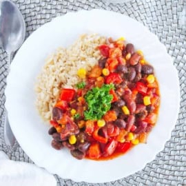 Rice and beans stew served on a white plate with a spoon on the side.