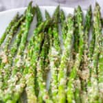 steamed asparagus with pecorino, served on a white plate
