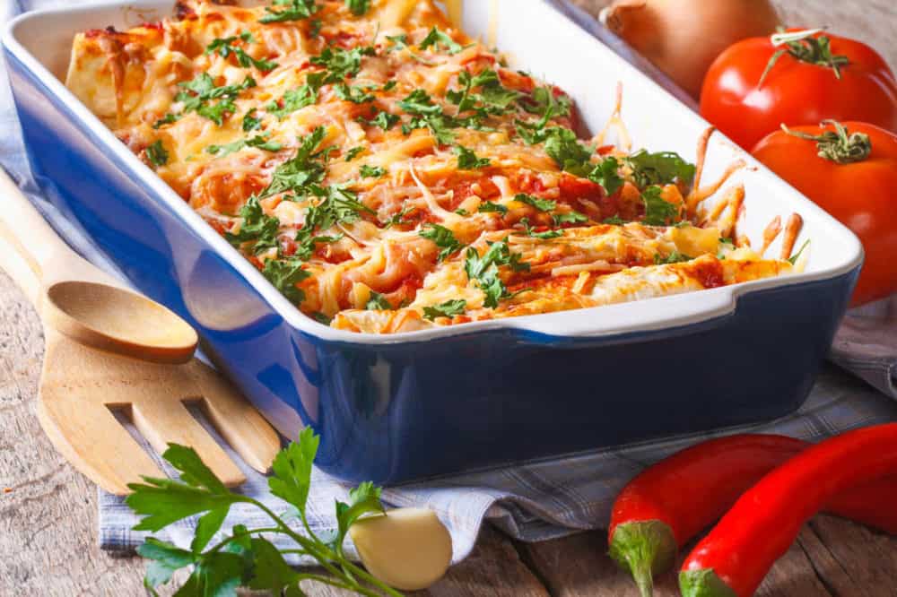 vegetarian enchilada casserole, in a baking dish with the ingredients on the table
