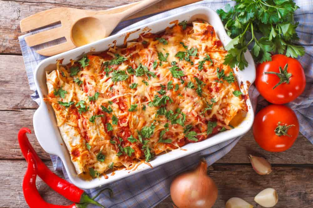 vegetarian enchilada casserole, in a baking dish with the ingredients on the table
