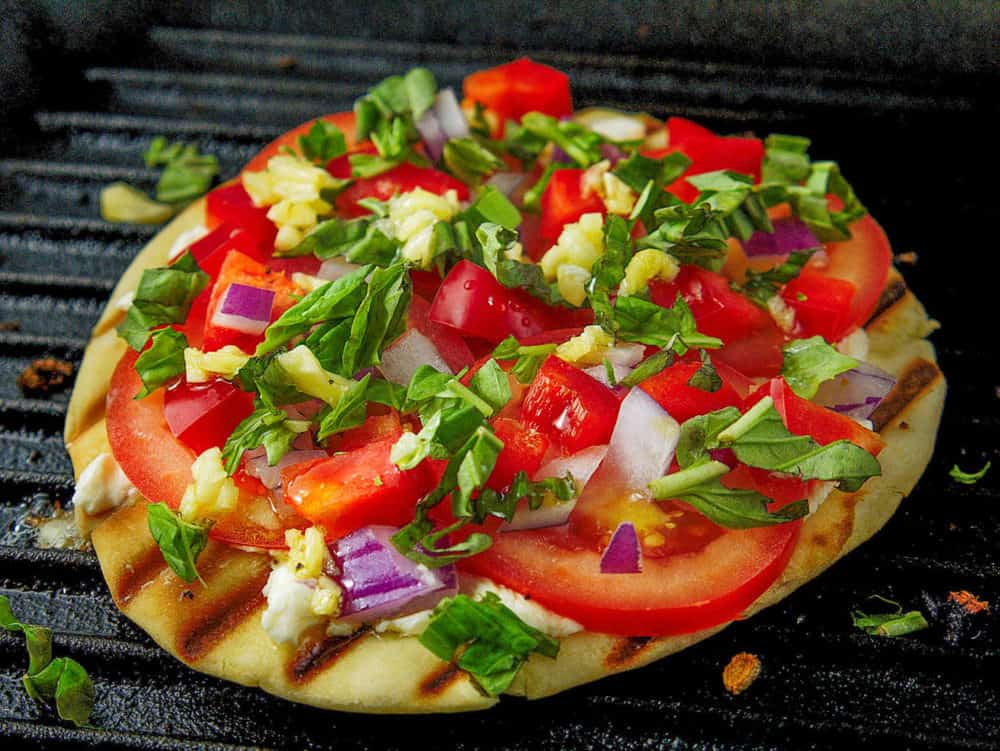 pita pizza with toppings cooking on a grill