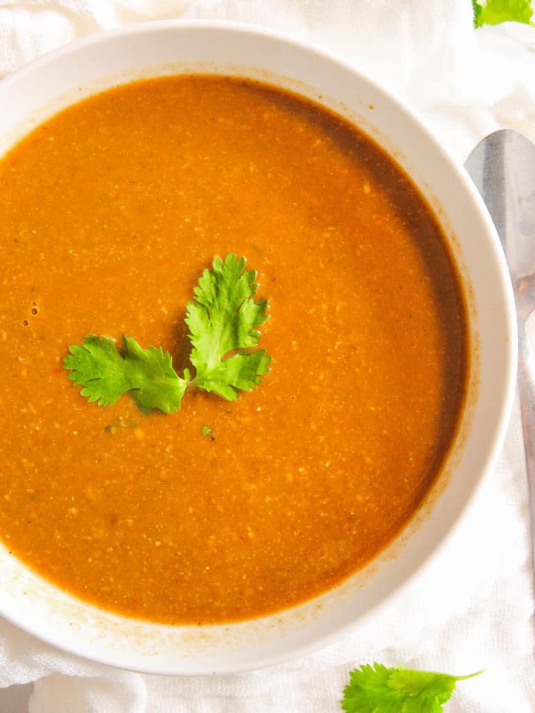 closeup of moroccan chickpea soup served in a white bowl with cilantro garnish