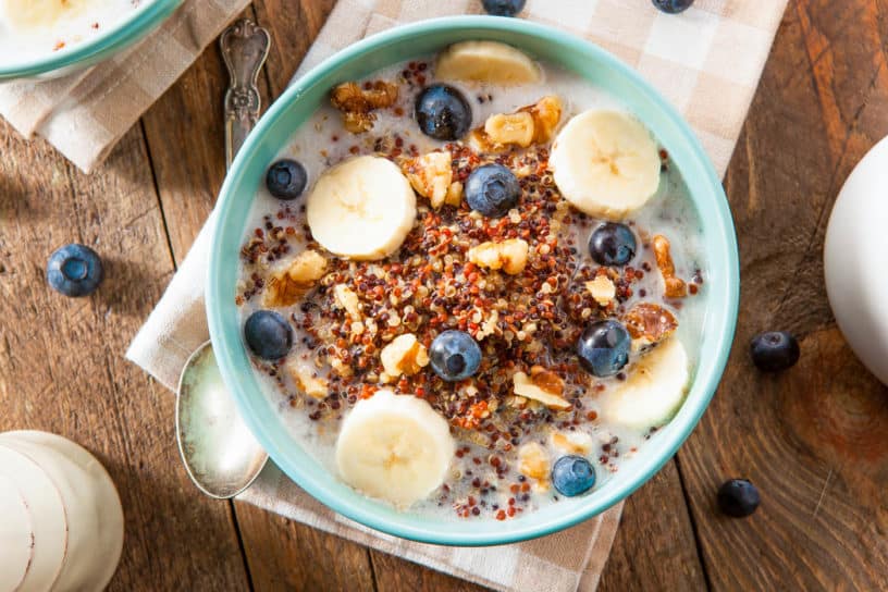 Quinoa Oatmeal with Nuts Milk and Berries, served in a blue bowl