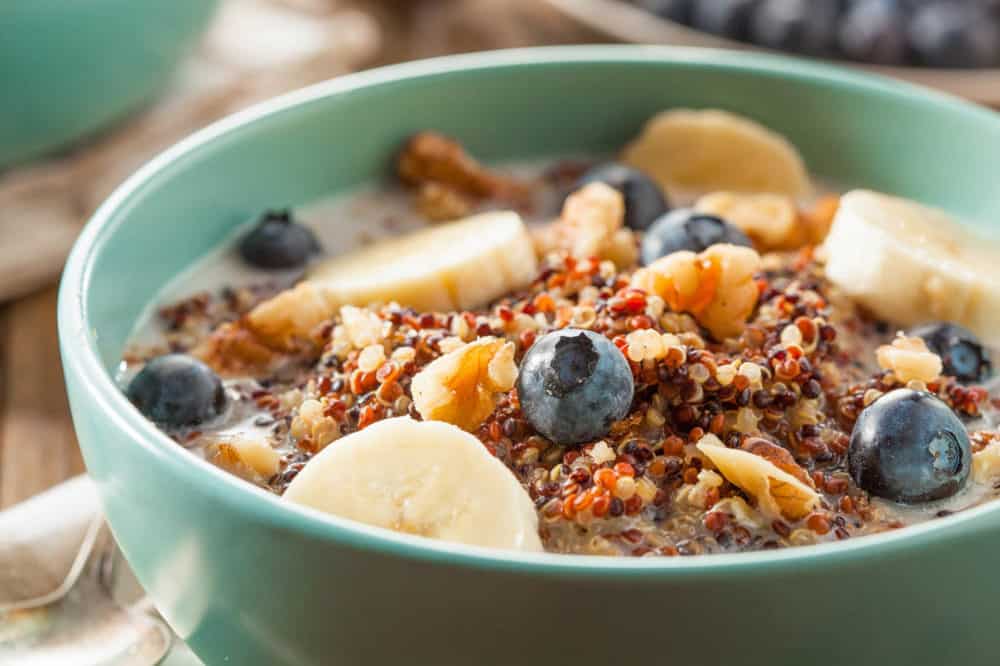 Quinoa Oatmeal with Nuts Milk and Berries, served in a blue bowl