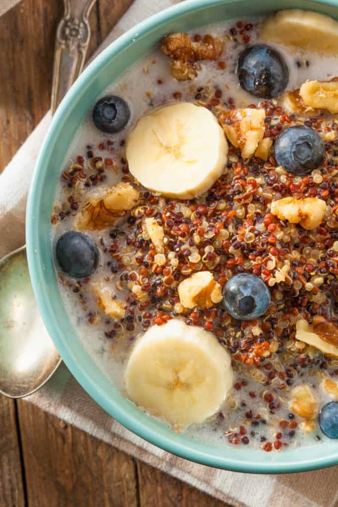 Quinoa Oatmeal with Nuts Milk and Berries, served in a blue bowl