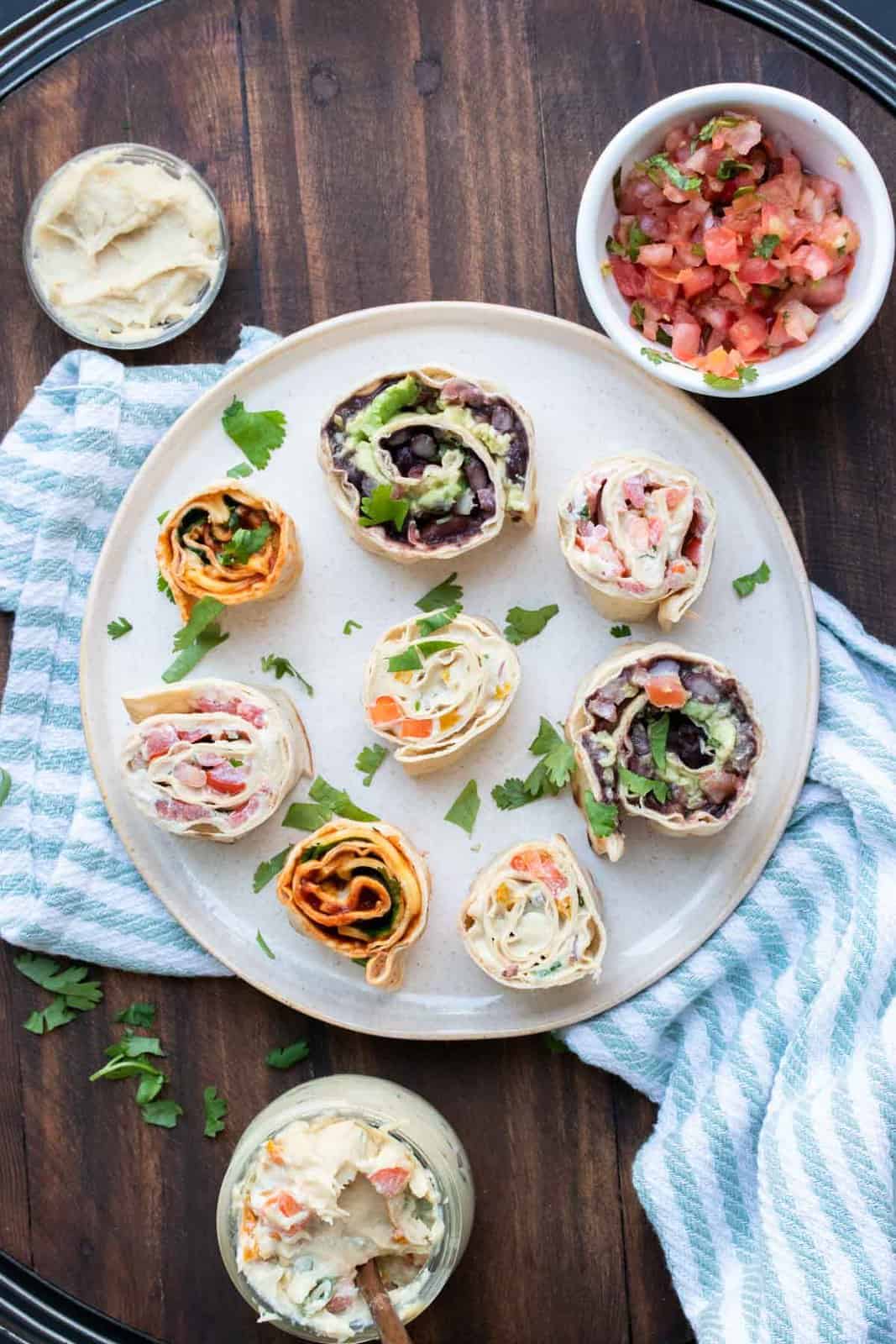 These vegan pinwheels are the perfect snack! Super kid friendly, versatile and easy enough the littles can make them too! #ad #vegansnacks #kidsrecipes Cream plate with different types of pinwheel roll ups on it