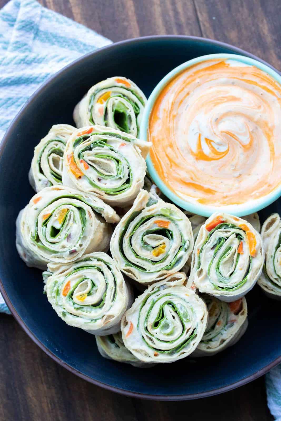 These vegan pinwheels are the perfect snack! Super kid friendly, versatile and easy enough the littles can make them too! #ad #vegansnacks #kidsrecipes Black plate with pinwheel rolls ups filled with lettuce, salsa and cream cheese
