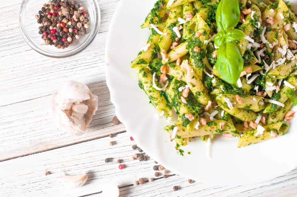 Vegetarian Pesto with Whole Wheat Pasta, topped with fresh basil, served on a white plate