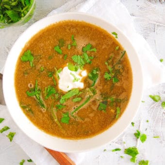 lebanese lentil soup with spinach, served in a white bowl with cilantro on top