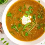 lebanese lentil soup with spinach, served in a white bowl with cilantro on top